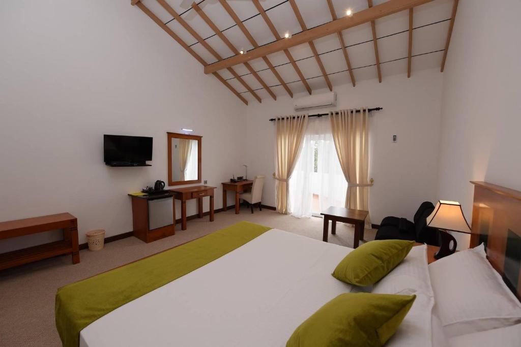 1 dormitorio con 1 cama grande y TV en Seasons Hotel en Kurunegala