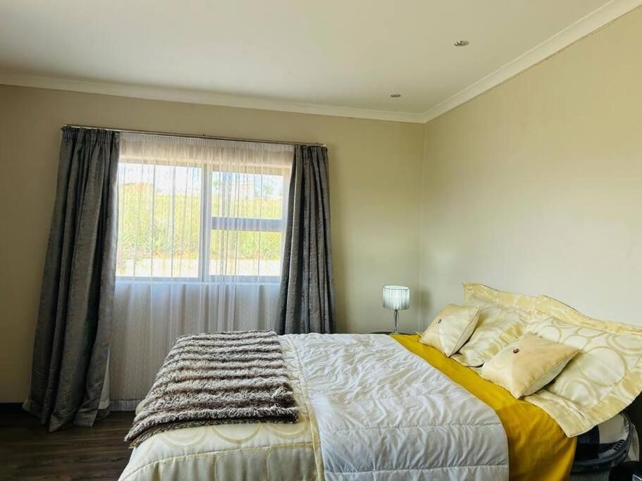 a bedroom with a large bed and a window at Cozy Farm 3BDRM 8 km ThabaBosiu in Maseru