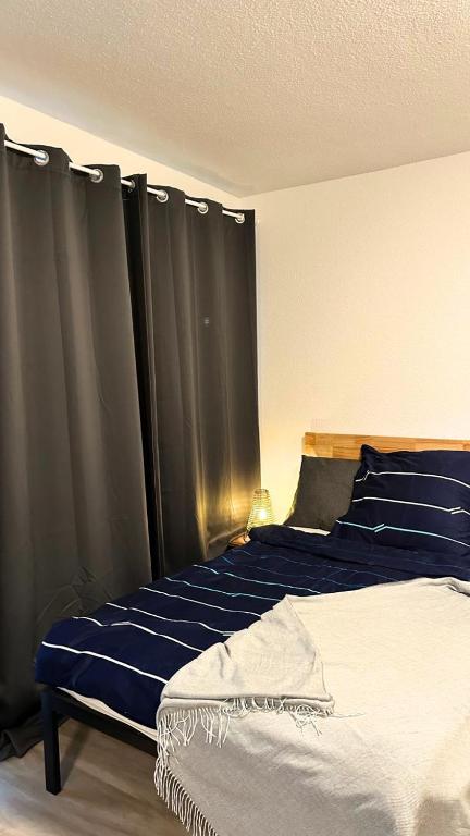 a bedroom with a bed with blue sheets and curtains at Modern Studio - perfect location in Duisburg