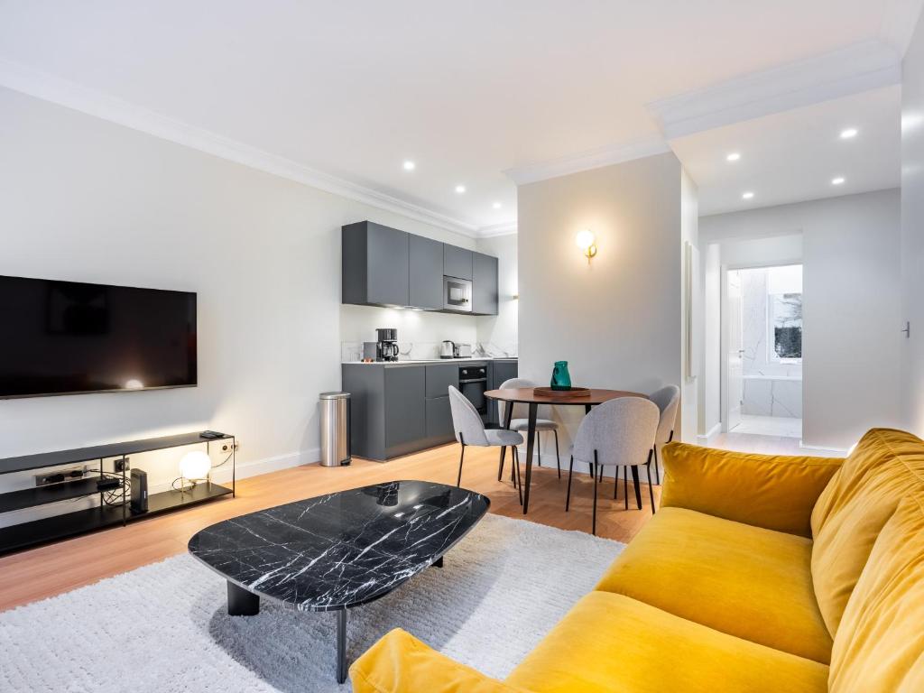 un salon avec un canapé jaune et une table dans l'établissement La Suite des Cordeliers - Résidence d'Exception, à Nancy