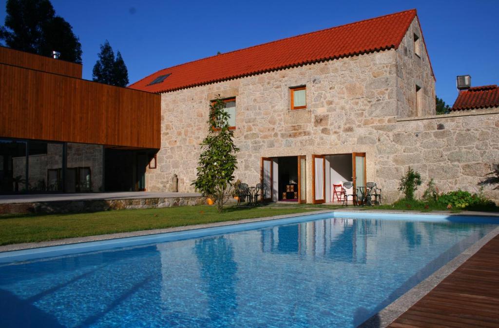 ein Haus mit einem Pool vor einem Gebäude in der Unterkunft Casa do Pomar - Eido do Pomar in Arcos de Valdevez