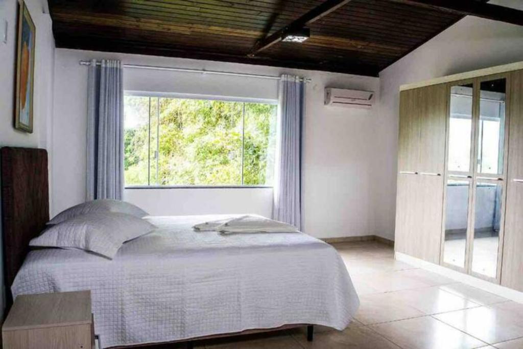 - une chambre avec un lit et une grande fenêtre dans l'établissement Pousada Sabores do Mar Laranjeiras, à Balneário Camboriú