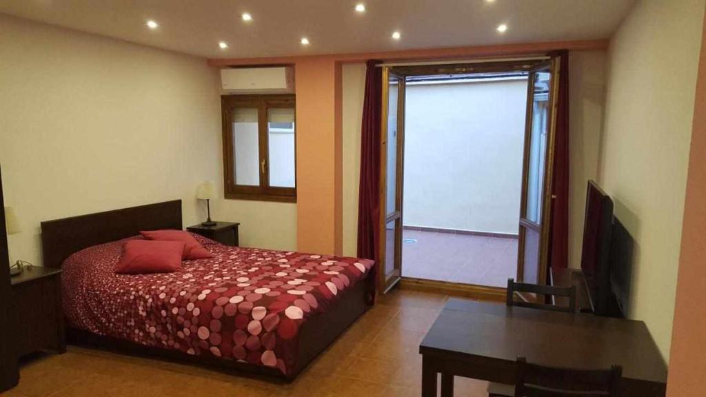 1 dormitorio con cama, escritorio y ventana en Apartamenticos Boggiero I, en Zaragoza