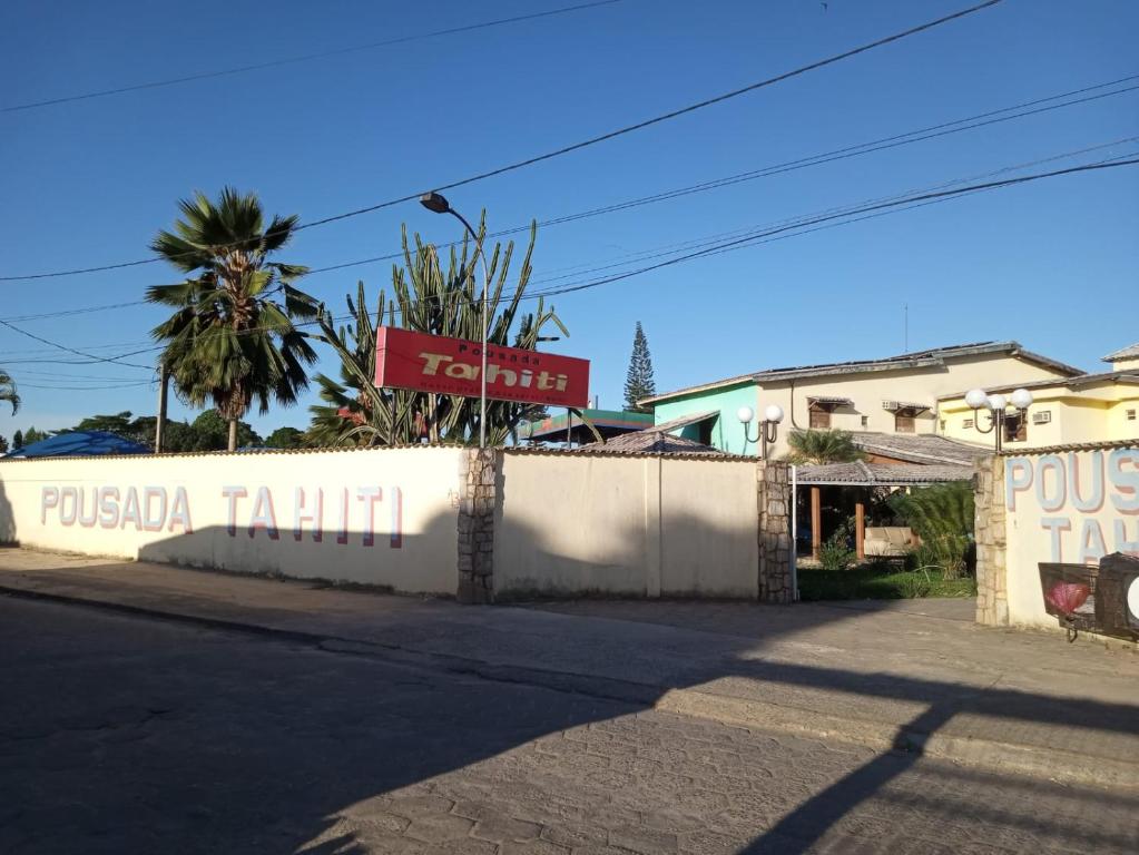una valla blanca con un letrero al lado de una calle en POUSADA TAHITI, en Pasto da Mata