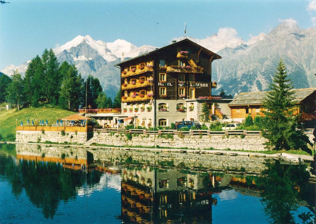 a large building next to a body of water at Hotel zum See in Grächen