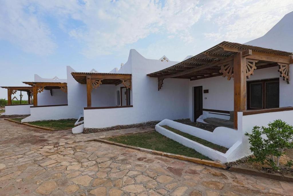 Casa con paredes blancas y techo de madera en Black Prince Hotel en Dahab