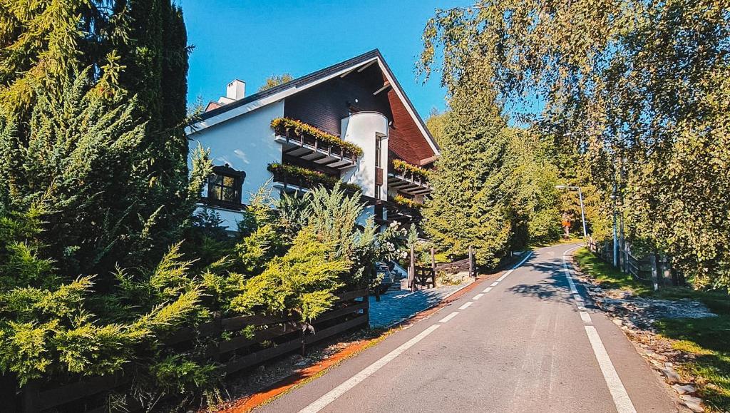 uma casa ao lado de uma estrada com árvores em Silvia Chalet Poiana Brasov em Brasov