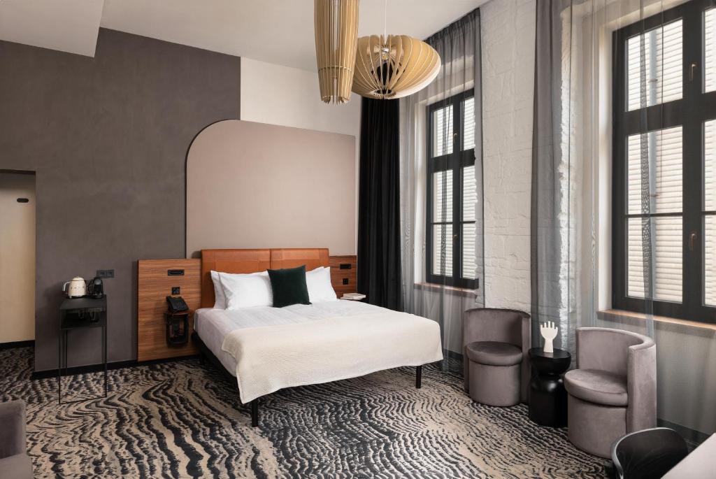 a bedroom with a bed and a chair and windows at Hotel GIN Budapest in Budapest