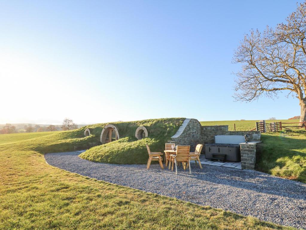 a patio with chairs and a grill in a field at Tan y Wawr- Onnen in Welshpool