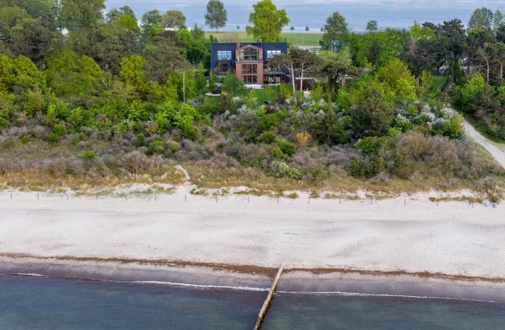 vue aérienne d'une plage avec une maison en arrière-plan dans l'établissement Villa Schmidt Apartments - Strandhaus direkt am Meer mit Sauna, Sport und Dünengarten IV, à Warnemünde