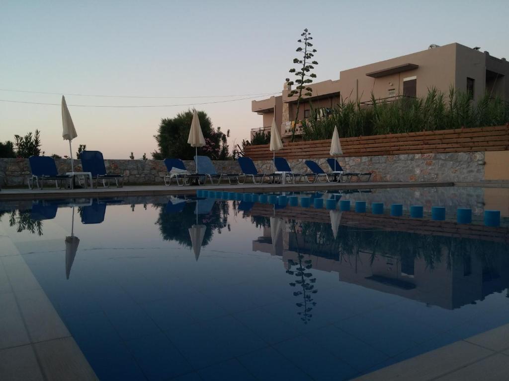 una piscina con algunas sillas y un edificio en Gerona Mare Apartments, en Gerani