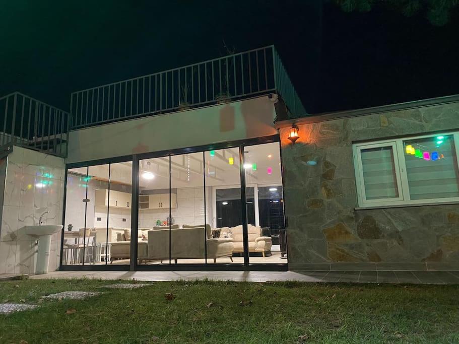 a house with glass windows and a living room at Uludağ manzaralı kış bahçesi in Panayır