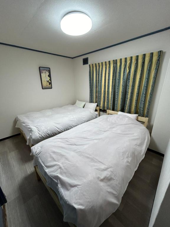 2 Betten in einem kleinen Zimmer mit weißer Bettwäsche in der Unterkunft 小樽民泊太田5号館 in Kita-hamachō