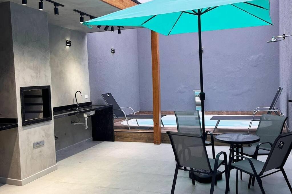 um quarto com uma mesa e uma cama com um guarda-chuva azul em Casa com piscina completa no ABC em São Bernardo do Campo