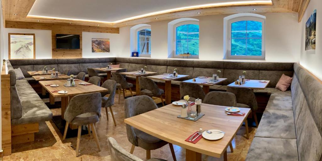 a restaurant with wooden tables and chairs and windows at Pension Weinberger in Obertauern