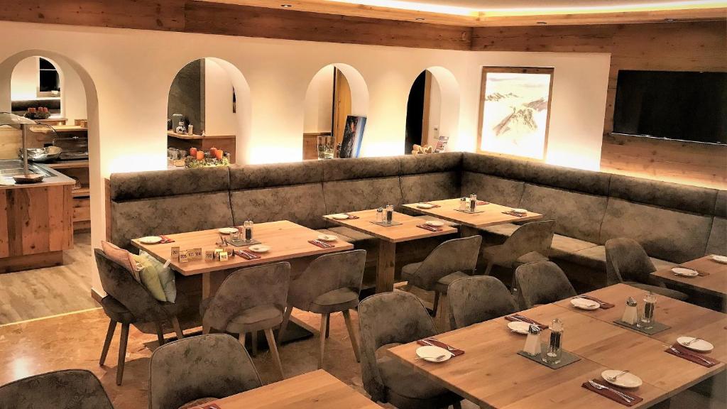 a restaurant with wooden tables and chairs in a room at Pension Weinberger in Obertauern