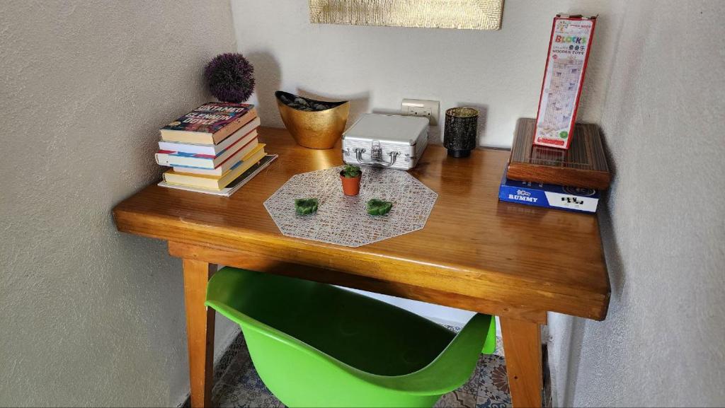 een houten bureau met boeken en een groene stoel bij VENICE by luxury Atitlan in San Pedro La Laguna