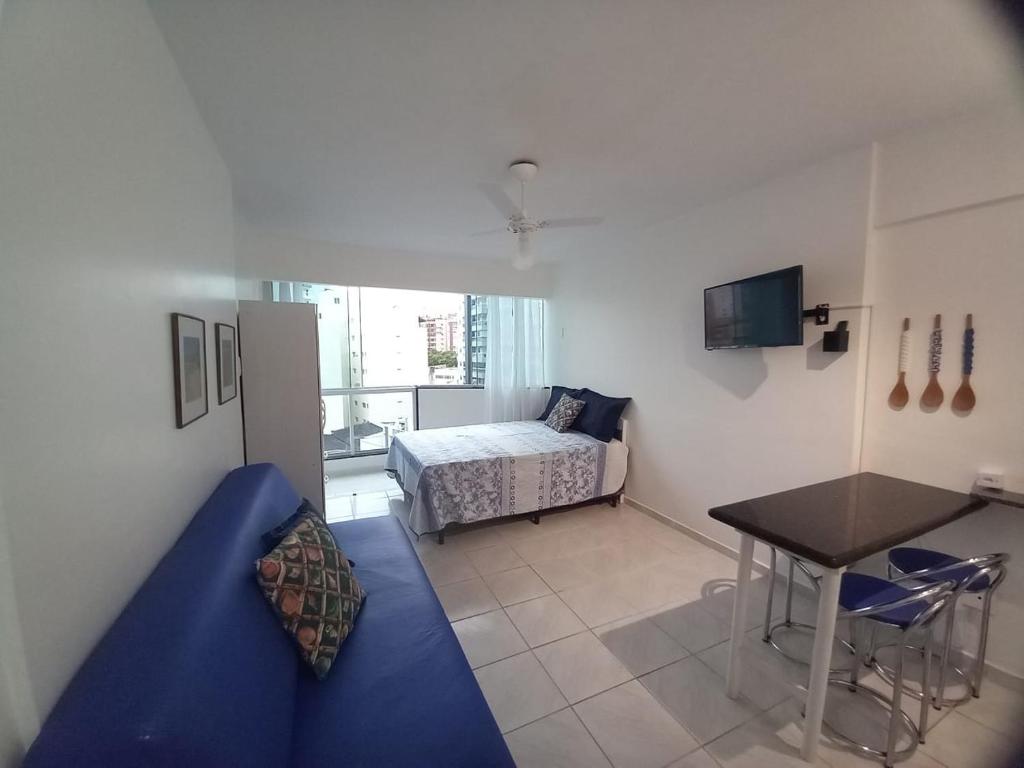a small room with a bed and a table and a desk at Apartamento 120 metros da praia in Guarapari