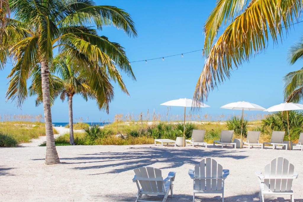 een groep stoelen en palmbomen op het strand bij Molloy Gulf Motel & Cottages in St Pete Beach
