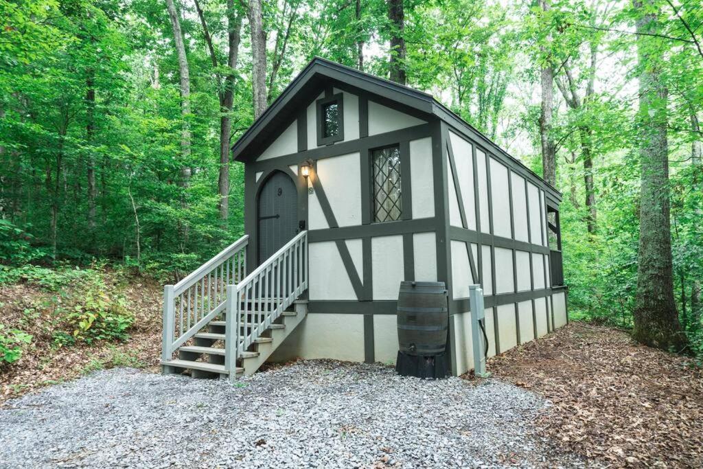 a small black and white building in the woods at Tiny Home Cottage Near the Smokies #9 Frieda in Sevierville