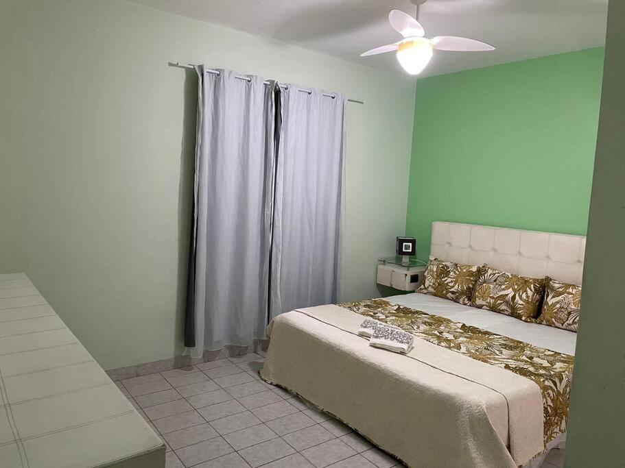 sypialnia z łóżkiem i wentylatorem sufitowym w obiekcie Apartamento a 100m. da Praia de Pitangueiras w mieście Guarujá