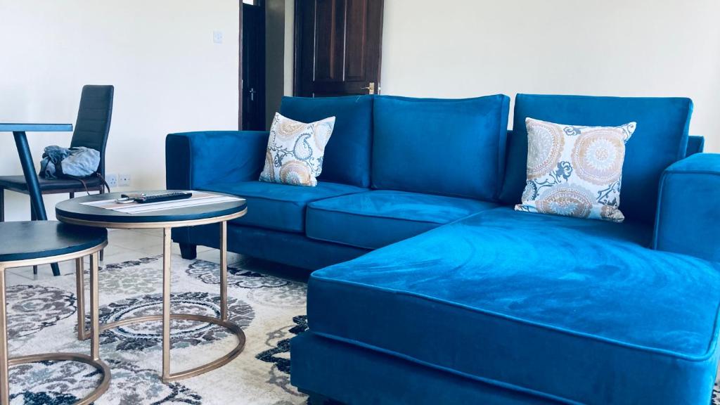 STUDIO MAIYAN في Busia: أريكة زرقاء في غرفة المعيشة مع طاولة