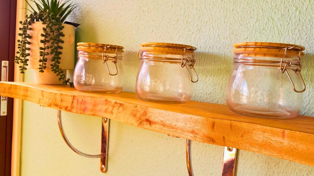 three jars on a wooden shelf in a room at Studio Karaïbes in Sainte-Anne