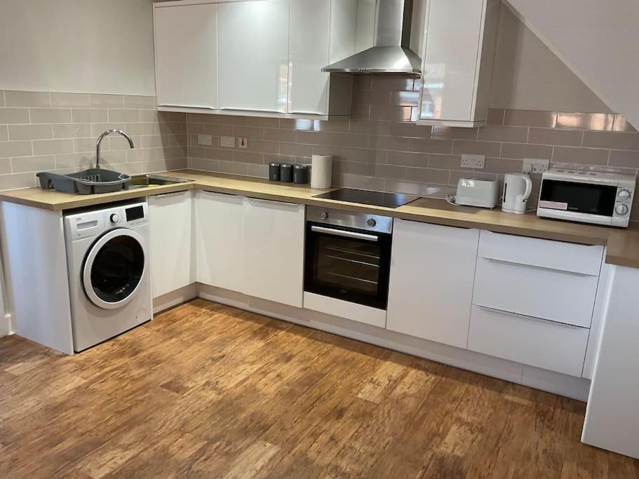 a kitchen with white cabinets and a washing machine at Rest Haven Lodge in Kettering
