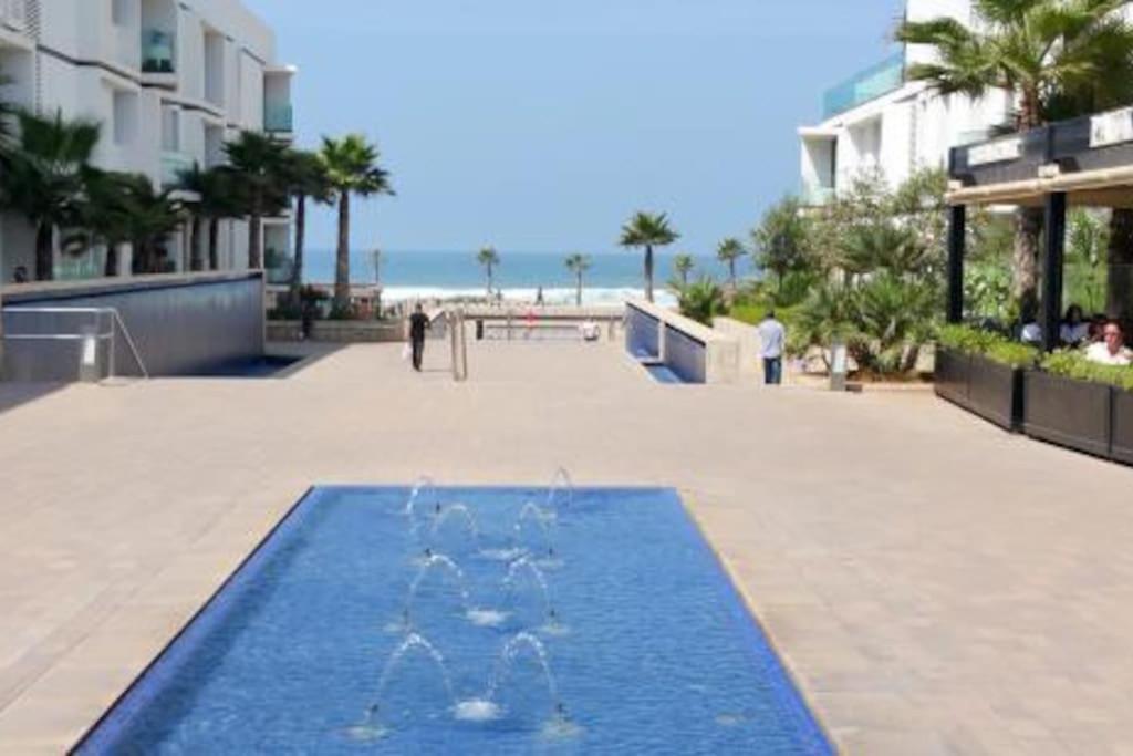 a pool of water on a sidewalk next to a beach at Luxury Ocean View Apartment - Anfa Place - in Casablanca