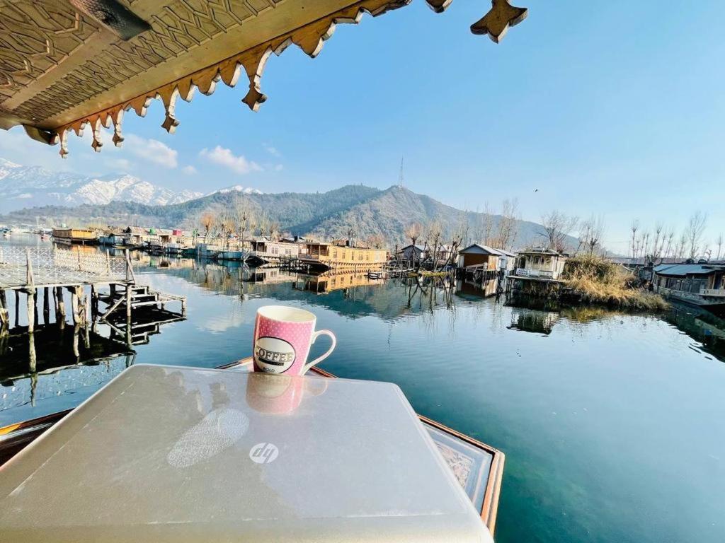 a cup of coffee sitting on a table next to the water at Houseboat Bendmeer Heritage in Srinagar