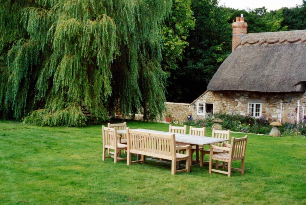uma mesa de piquenique e cadeiras em frente a uma casa em Afton Thatch: Beautiful Thatched Family Cottage em Freshwater
