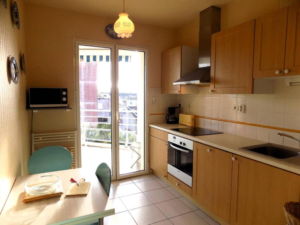 a kitchen with wooden cabinets and a table and a window at Royan - Résidence VILLA BRACELLI - APPARTEMENT SPACIEUX - Centre-ville in Royan