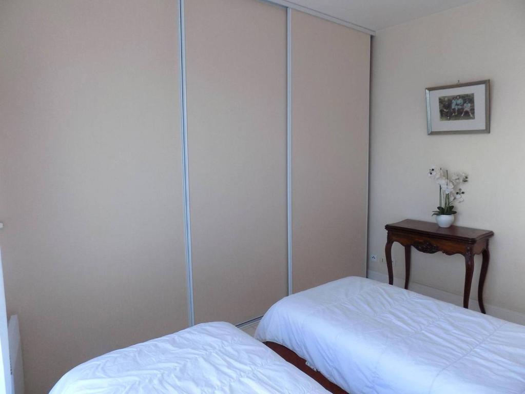 a room with two beds and a table in it at Royan - Résidence VILLA BRACELLI - APPARTEMENT SPACIEUX - Centre-ville in Royan