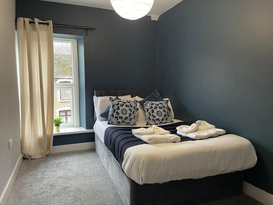 a bedroom with a bed with blue walls and a window at Dumfries House By MGroupSA in Treherbert