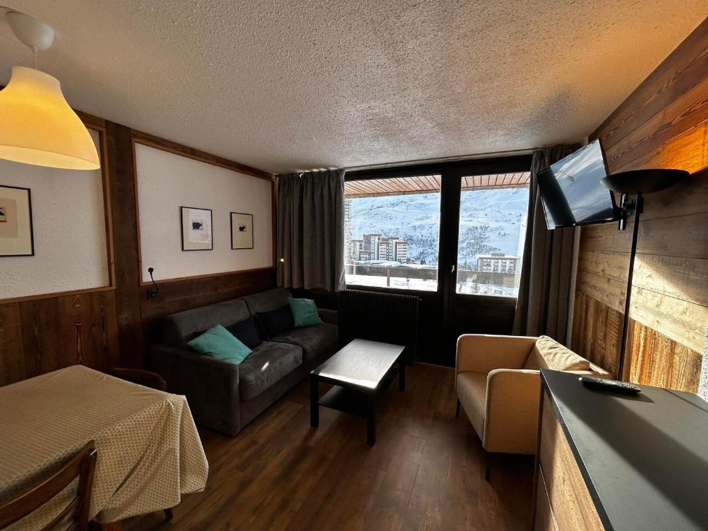 un salon avec un canapé, une table et une télévision dans l'établissement Appartement au pied des pistes pour 4 pers, balcon sud, centre des Menuires, proche commerces - FR-1-452-184, aux Menuires
