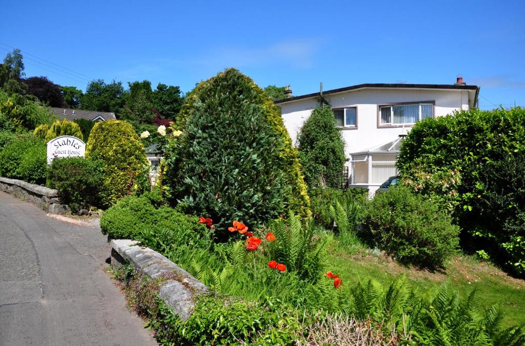 ogród z kwiatami i krzakami obok domu w obiekcie Stables Guest House w mieście Newton Stewart
