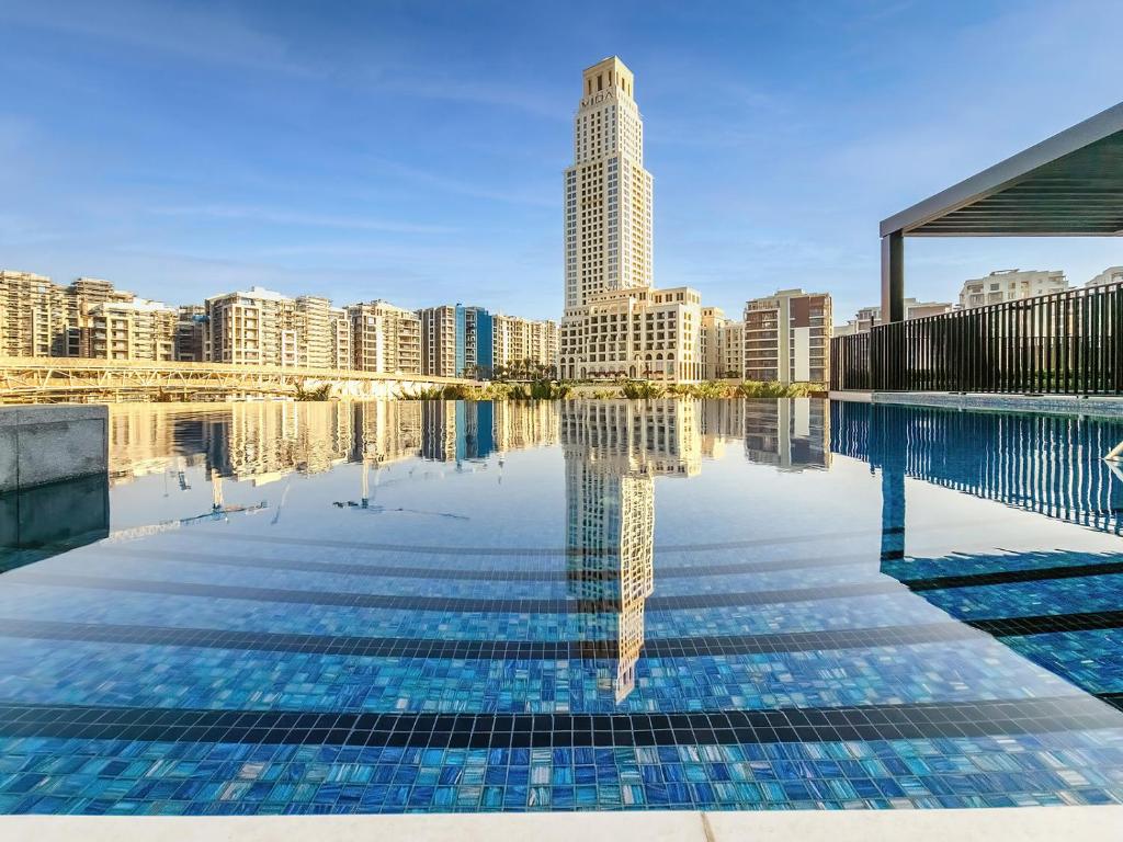 een zwembad met een skyline van de stad op de achtergrond bij Palace Residences, Dubai Creek Harbour in Dubai
