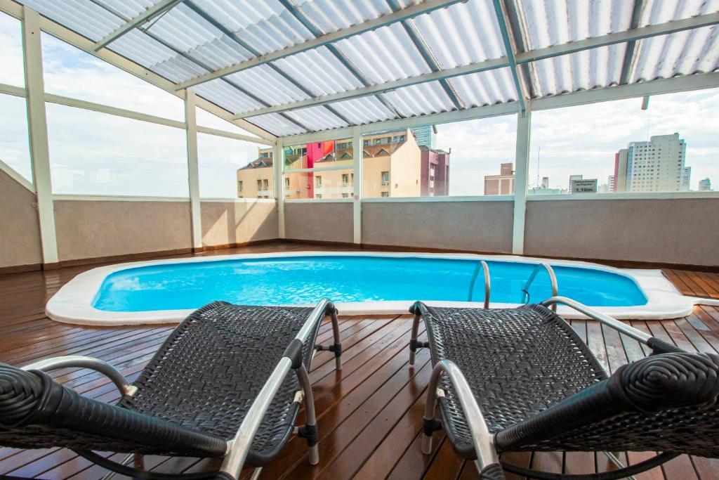 einen Balkon mit 2 Stühlen und einem Pool in der Unterkunft Hotel Golden Park Curitiba By Nacional Inn in Curitiba