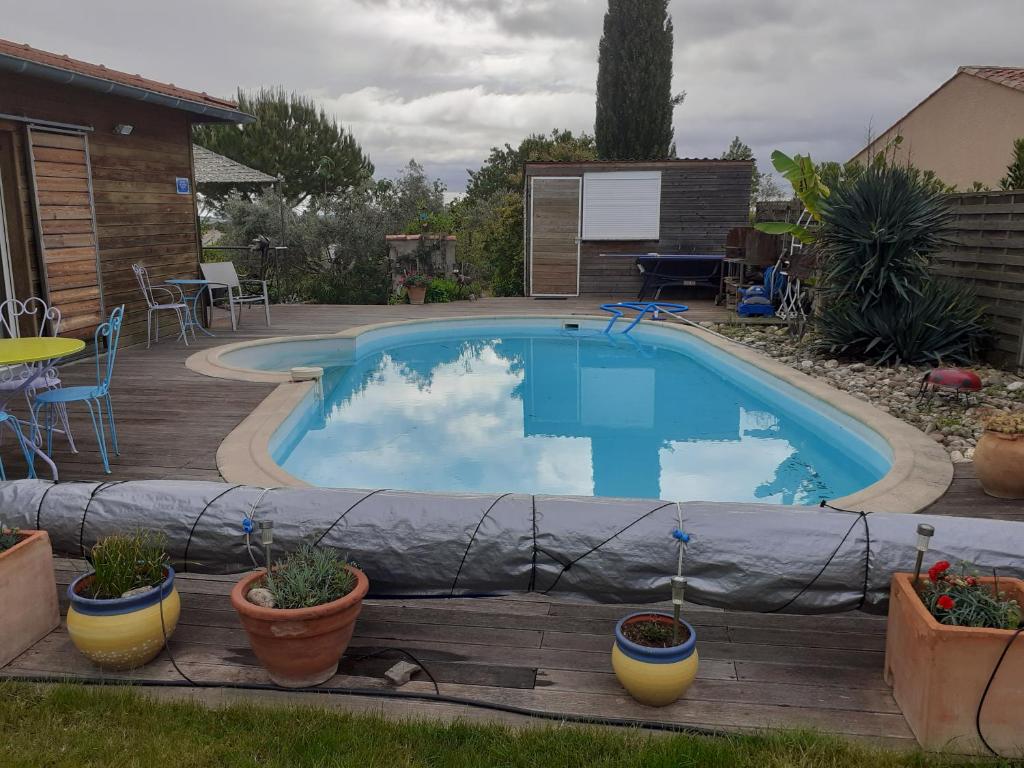a swimming pool with potted plants on a wooden deck at Petit Paradis chez Pascale et Bernard in Cazouls-lès-Béziers