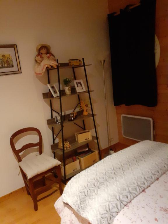 a bedroom with a shelf and a bed and a chair at Petit Paradis chez Pascale et Bernard in Cazouls-lès-Béziers