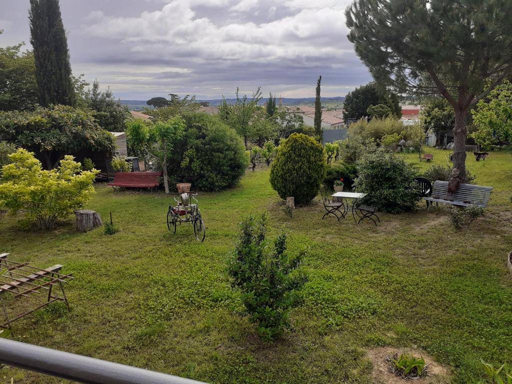 a view of a garden with benches and trees at Petit Paradis chez Pascale et Bernard in Cazouls-lès-Béziers