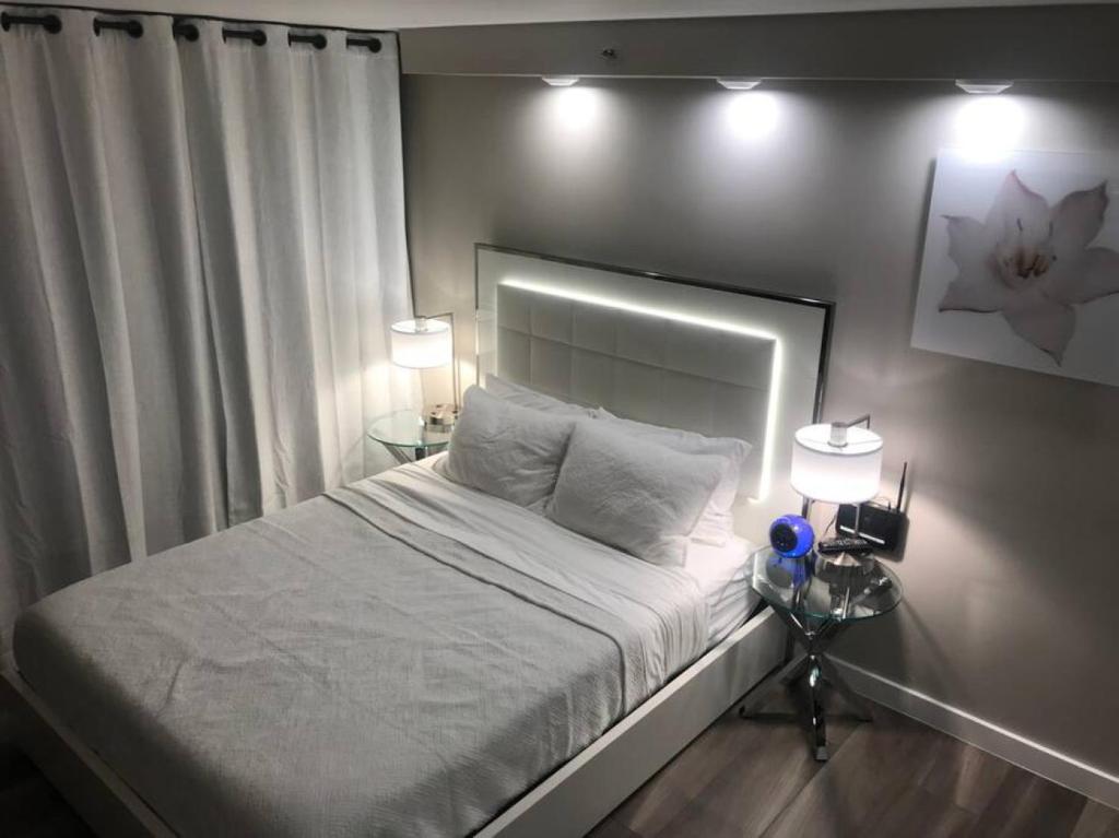 1 dormitorio con 1 cama con 2 lámparas y 2 mesas en Private Modern Luxury Studio B Waikiki Ocean View, en Honolulu