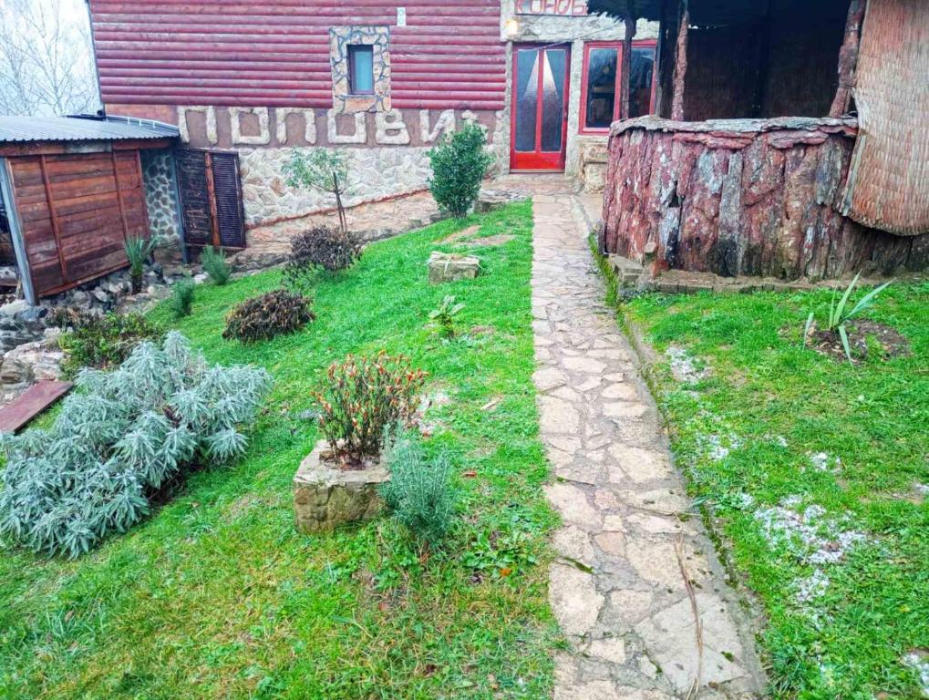 un jardín con algunas plantas y una casa en Smeštaj Popović en Perućac