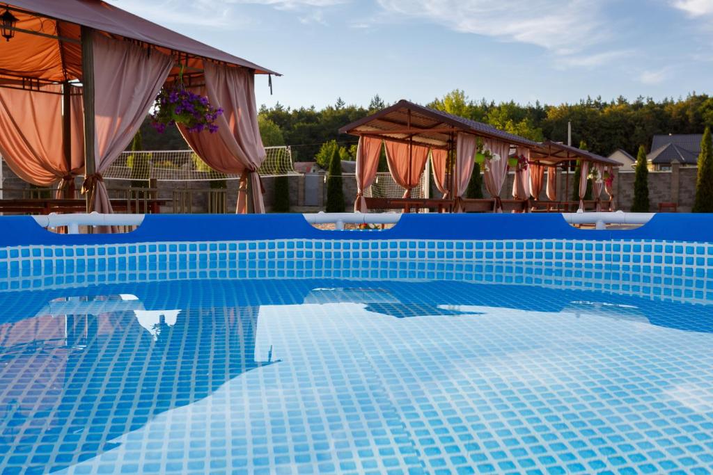 een blauw betegeld zwembad met parasols bij Zolota Pidkova in Loetsk
