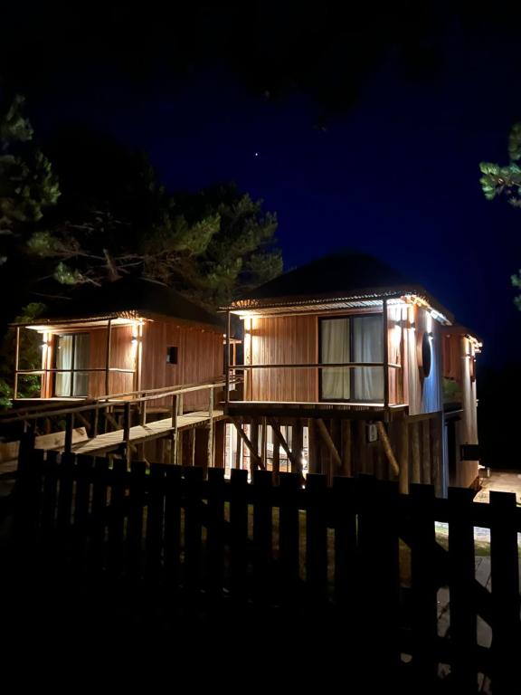 a cabin with lights on the deck at night at Aldea La Nacha in José Ignacio