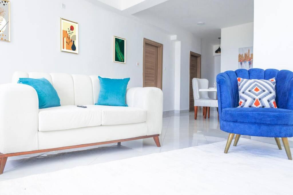 uma sala de estar com um sofá branco e cadeiras azuis em Angani Apartment em Mombasa