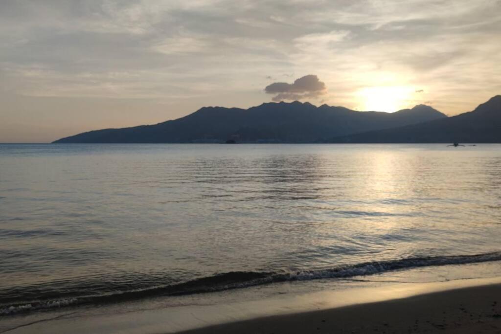 een zonsondergang over de oceaan met bergen op de achtergrond bij Baloy beach house in Olongapo
