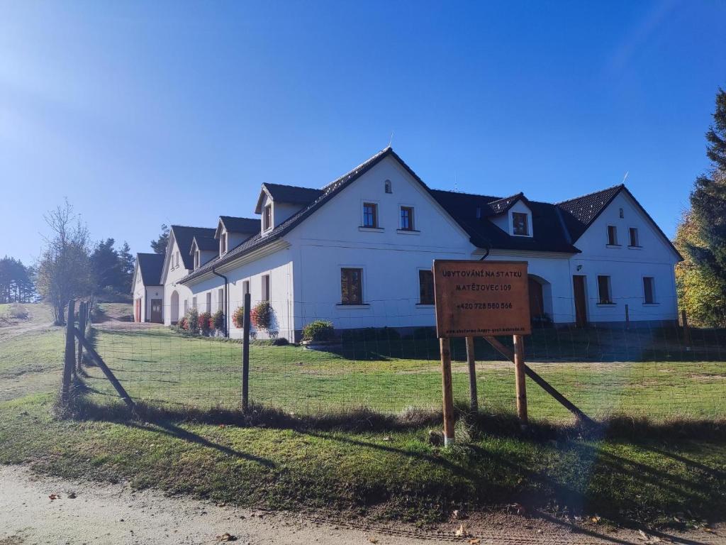 una casa blanca con un cartel delante en Matějovec 109 & Ubytování Na statku, en Český Rudolec