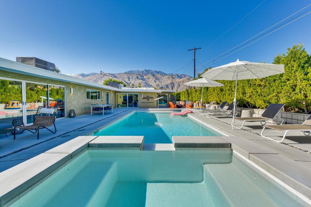 a swimming pool with chairs and an umbrella at Luxe Palm Springs Home - Close to Downtown! in Palm Springs
