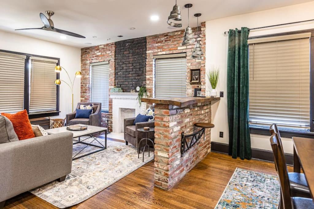 a living room with a brick wall and a fireplace at Pleasantly Plush - Quality and Comfort Downtown in Tulsa